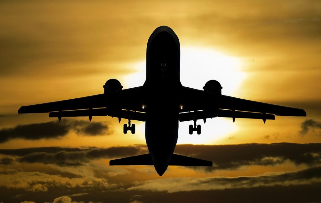 Flugzeug im Landeanflug vor einem orangefarbenen Sonnenuntergangshimmel